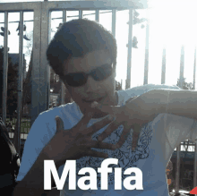 a man wearing sunglasses and a white shirt that says mafia