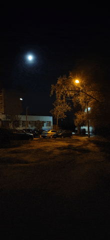 a parking lot at night with a full moon in the background