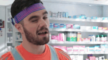 a man wearing a headband is singing in front of a pharmacy