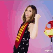 a woman in a black dress with a red and yellow scarf around her neck has a fist in the air