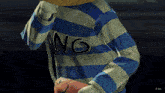 a person wearing a blue and white striped shirt with the letters ng on the front