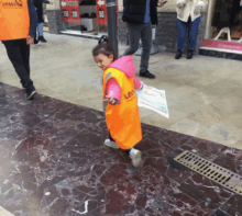 a little girl wearing an orange vest that says losev