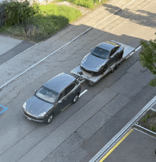 a gray car is being towed by another car on a trailer