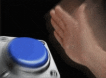 a person 's hand is touching a blue button