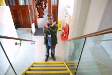 a man crosses his arms in front of a yellow sign that says caution wet floor