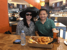 a man and woman sit at a table with a bottle of aquafina water in front of them