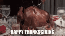 a person is cutting a turkey on a table with the words `` happy thanksgiving '' written above it .