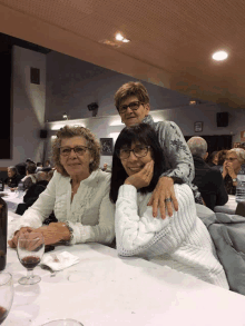 three women sit at a table with glasses on