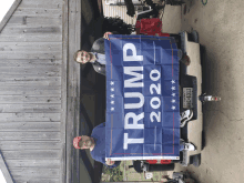 two men are holding a trump 2020 flag