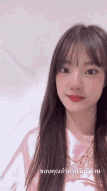 a girl in a pink shirt is looking at the camera with a caption in thai