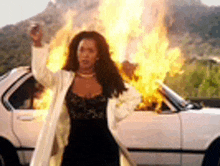 a woman is standing in front of a car on fire .