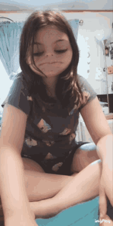 a young girl is sitting on a bed with her legs crossed and making a funny face ..