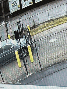 a black truck is parked in front of a fence that says west gates / parking