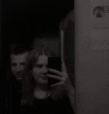 a man and a woman are taking a selfie together in a mirror .