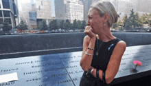 a woman is crying in front of a wall with names on it including timothy matthew welly