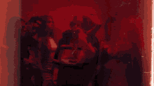 a painting of a group of people in a dark room with a red background