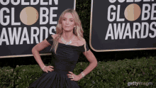 a woman in a black dress is standing in front of a sign that says ' golden globe awards '