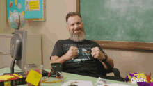 a man with a beard is sitting at a desk in front of a chalkboard with the word podcast on the bottom