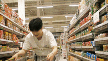 a man pushing a shopping cart in a grocery store with a sign that says ' a ' on it