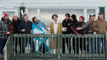 a group of people standing on a balcony in front of a house with a sign on it that says ' post & guest '