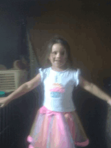 a little girl wearing a white shirt with a cupcake embroidered on it