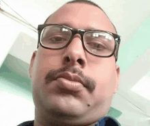 a man wearing glasses and a mustache is making a funny face .