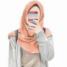 a woman wearing a hijab is taking a selfie with her cell phone .