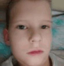 a close up of a young boy 's face while laying in bed .