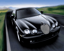 a black jaguar is driving down a road with mountains in the background