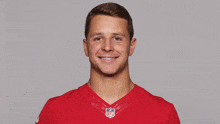 a man wearing a red nfl jersey smiles for a picture