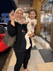 a woman carrying a baby with a fendi bag