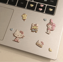 a silver laptop with stickers on it including hello kitty keroppi and my melody