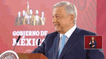 a man in a suit and tie stands at a podium in front of a sign that says " gobierno de mexico "