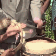 a man in a suit is holding a snake in his hand while a woman holds a bucket of rice .