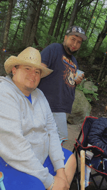 a man wearing a cowboy hat is sitting next to another man wearing a shirt with a lion on it ..