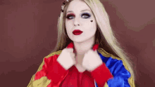 a woman in a harley quinn costume is wearing a red , yellow and blue jacket .