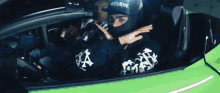 a man wearing a black mask is driving a green car .