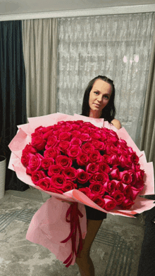 a woman holds a large bouquet of red roses