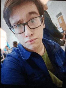 a young man wearing glasses takes a selfie