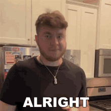 a man wearing a black shirt and a necklace is standing in a kitchen with the word alright above him