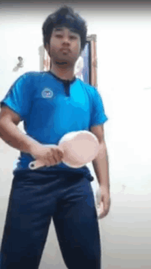 a man in a blue shirt is holding a pink brush in his hands .