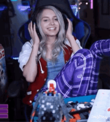 a woman wearing headphones is smiling while sitting in a gaming chair .