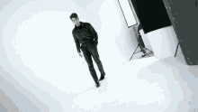 a man in a black shirt and black pants is walking on a white surface