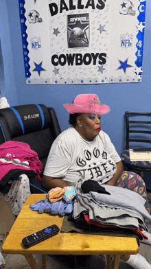 a woman wearing a pink cowboy hat is sitting in front of a dallas cowboys sign