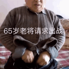 an older man is sitting on a bed with chinese writing on the bottom of his shirt