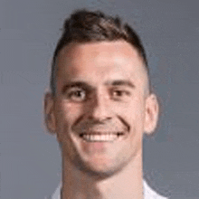 a close up of a man 's face smiling against a grey background .