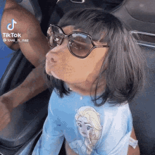 a little girl wearing sunglasses and a blue shirt with elsa on it