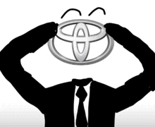 a man in a suit and tie is holding a toyota logo in front of his head