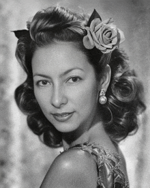 a woman with a rose in her hair is wearing pearl earrings