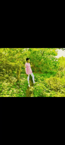 a man in a pink shirt and white pants is standing in a field